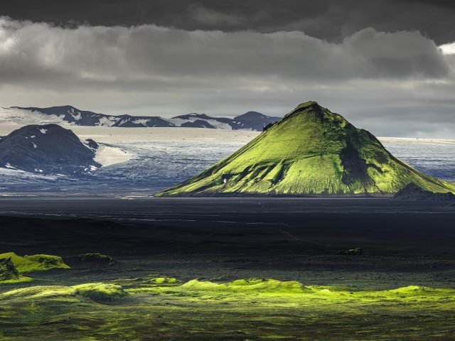 Зеленая покрытая гора фон заснеженной горы с зелеными полями природа