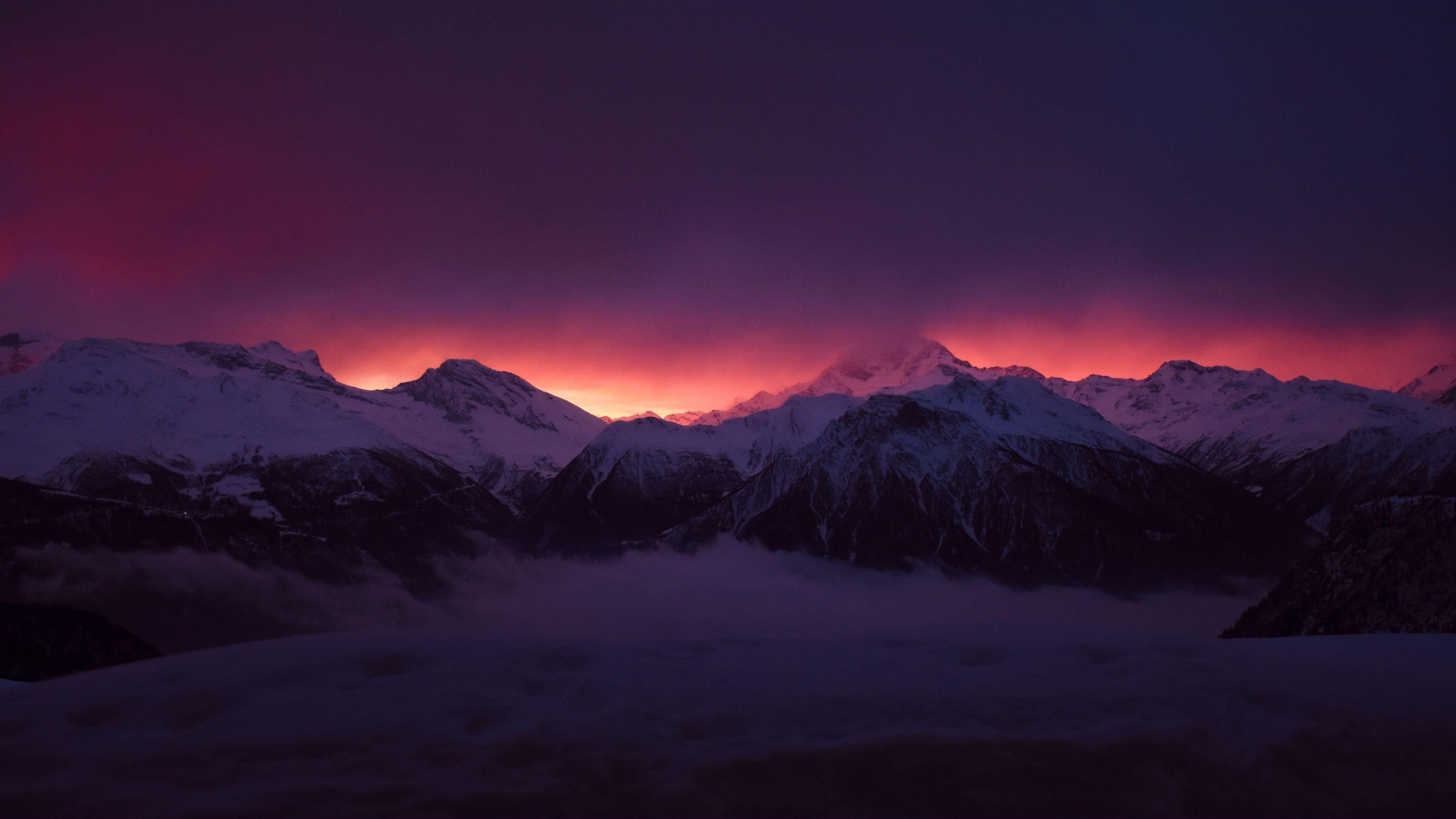 Заснеженные вершины гор туман под фиолетово черным облачным небом природа обои скачать