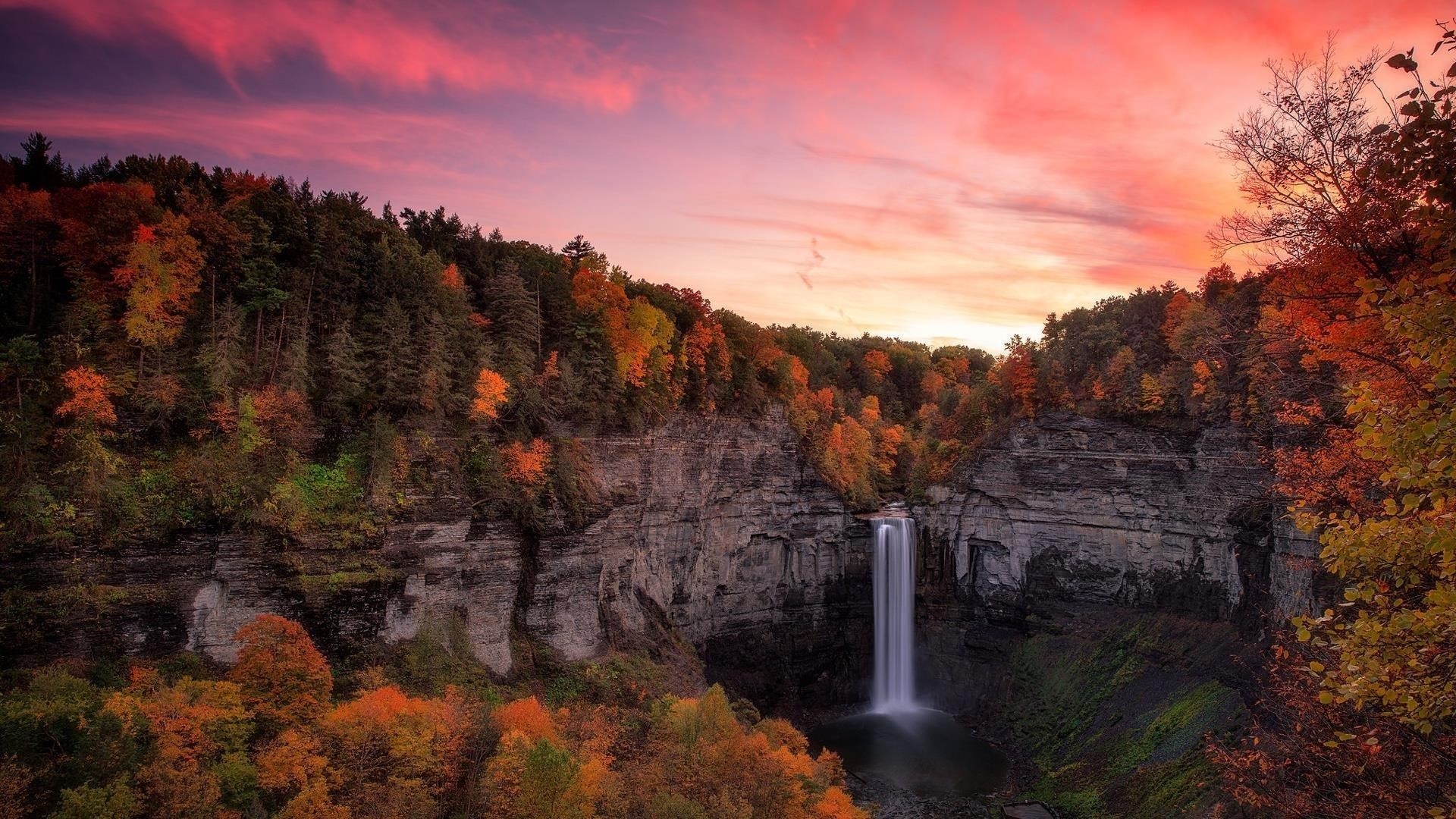 Водопад между осенними деревьями покрытый лесом с красочной закатной природой обои скачать