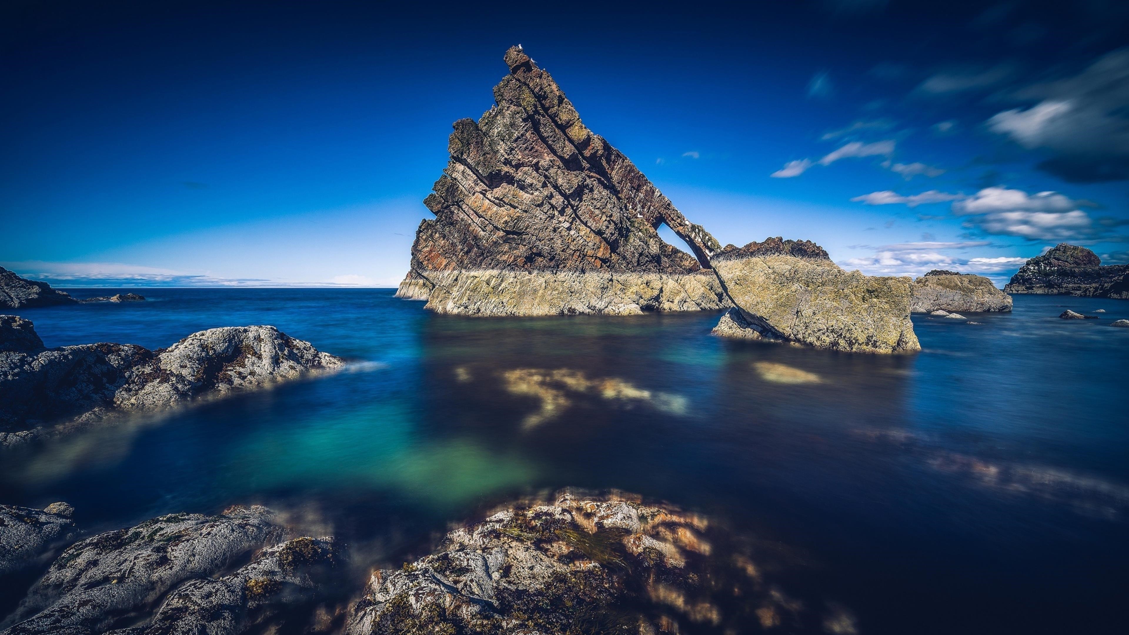 Скала посреди океана под голубым небом природа обои скачать