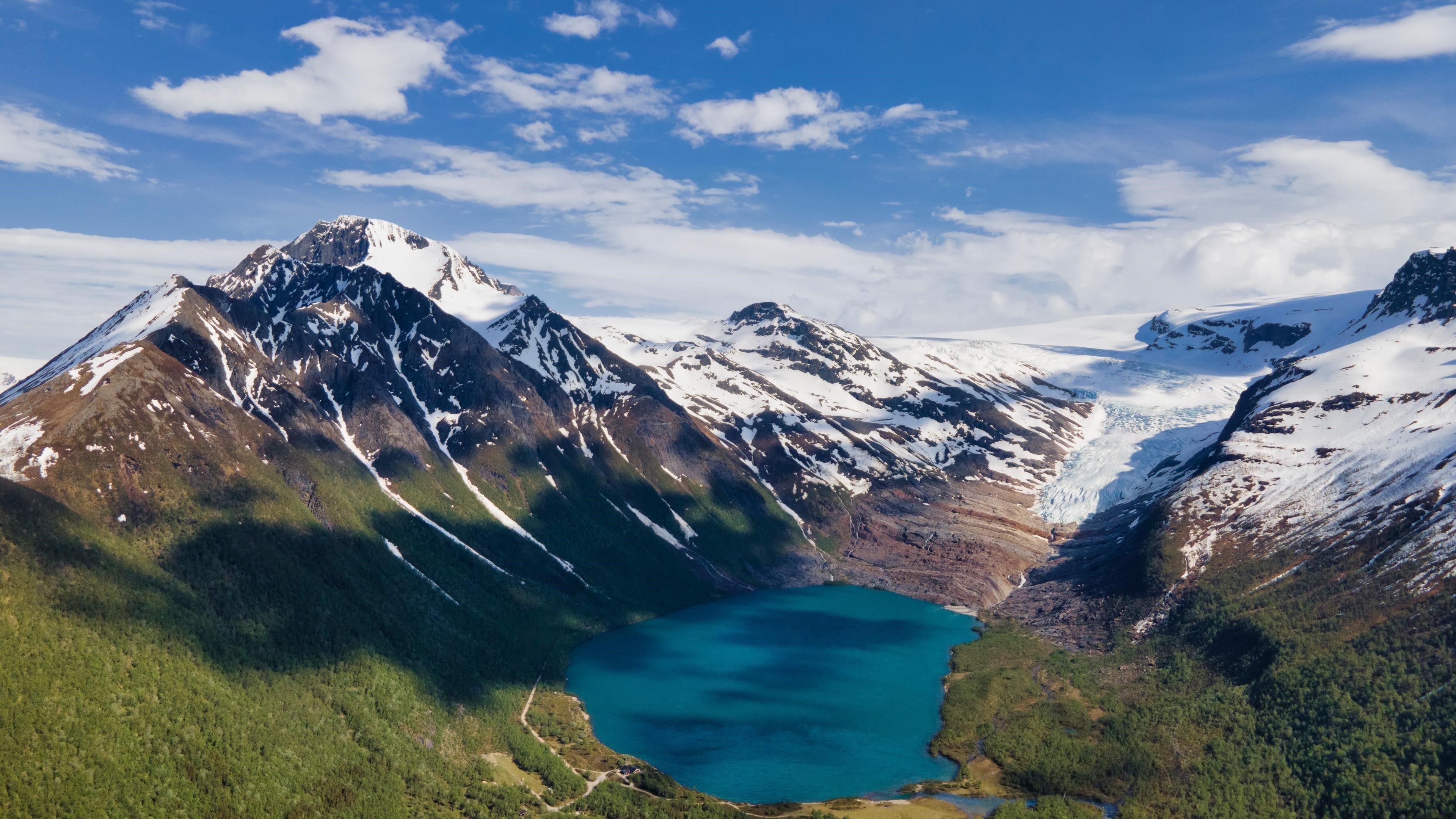Озеро окруженное белыми покрытыми горами под облачным голубым небом в свартисватнете Норвегия природа обои скачать